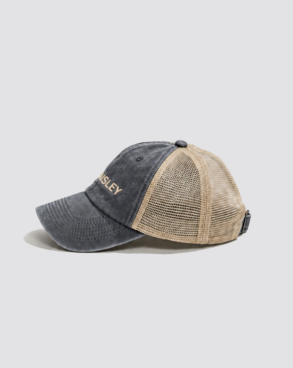 Side view of the Daisley washed slate blue trucker cap with cream mesh panels and a curved brim